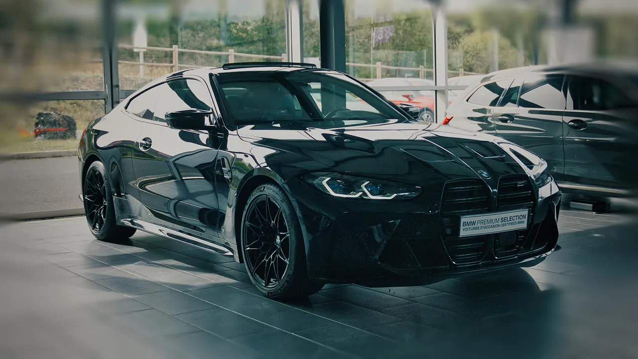 BMW M4 noire exposée dans le hall vitré d'une concession automobile