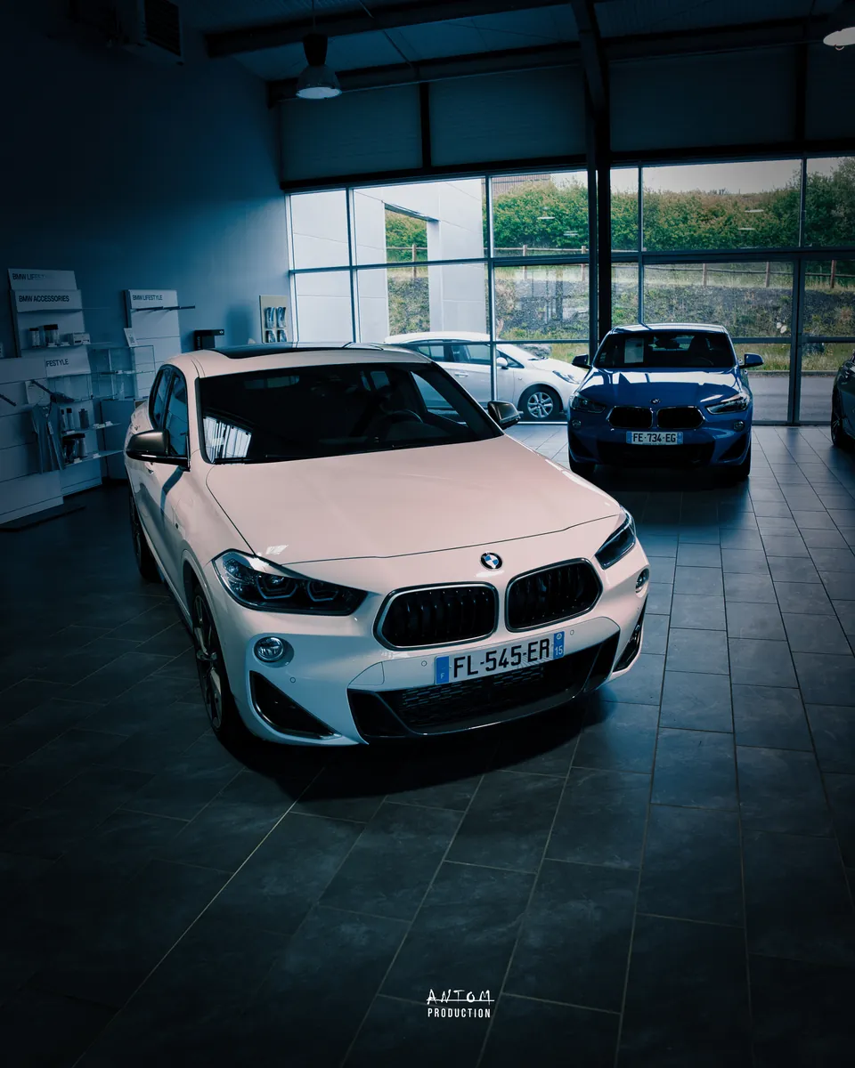 BMW X2 blanche photographiée dans le hall d'exposition d'une concession