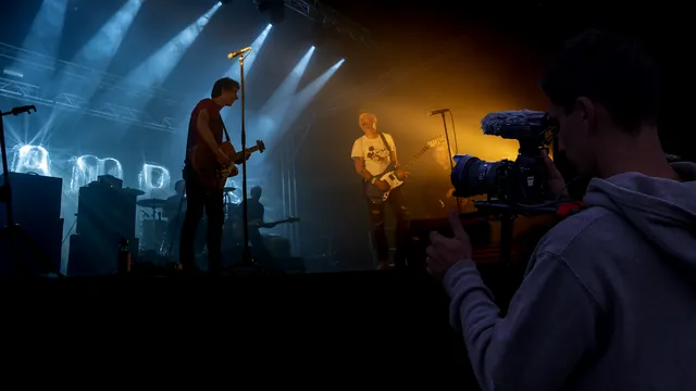 Captation vidéo d'un concert : opérateur, caméra et micro au bord de la scène