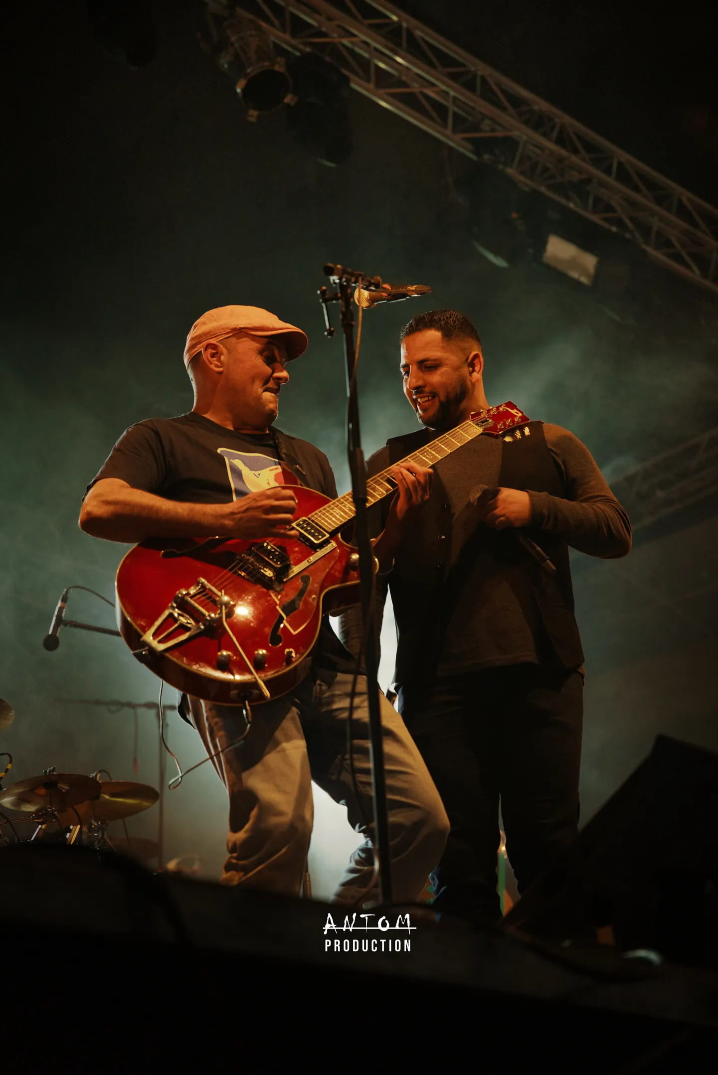 Deux musiciens complices sur scène, guitare rouge à la main, pendant un concert