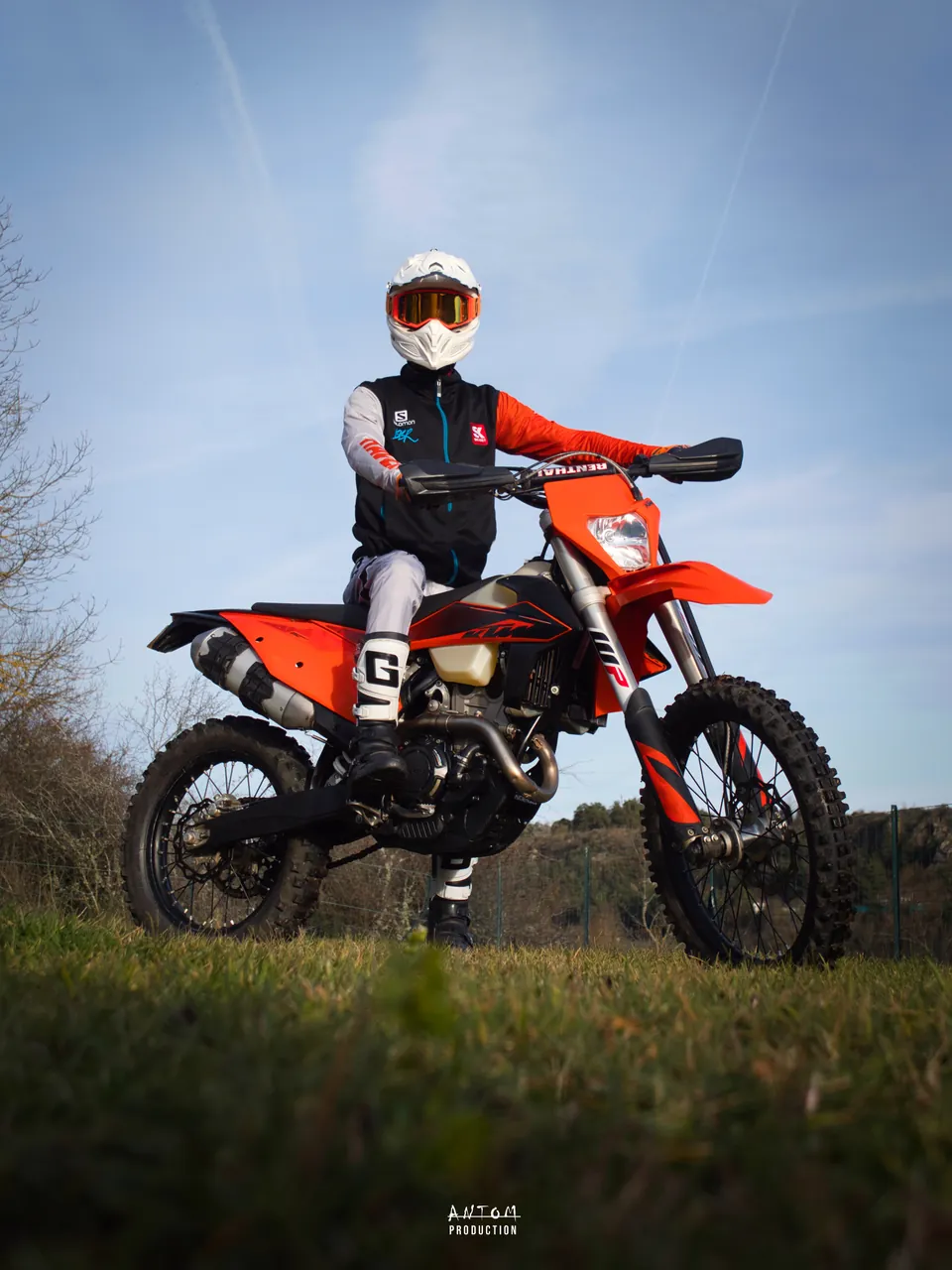 Pilote en tenue posant sur sa moto d'enduro orange