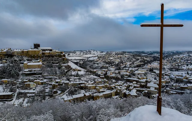 Panorama de Saint-Flour sous la neige avec une croix au premier plan